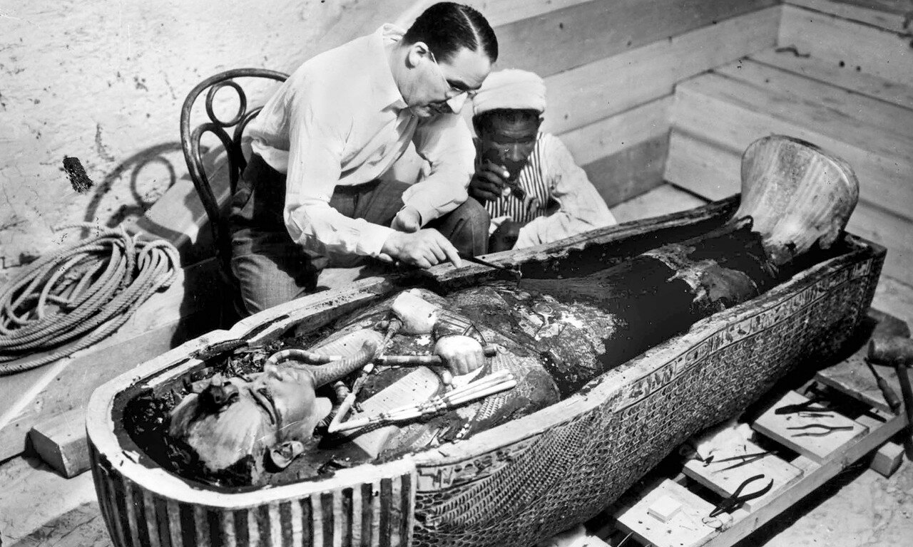 Британский археолог Говард Картер и египетский помощник исследует саркофаг с телом фараона Тутанхамона в Долине царей близ Луксора